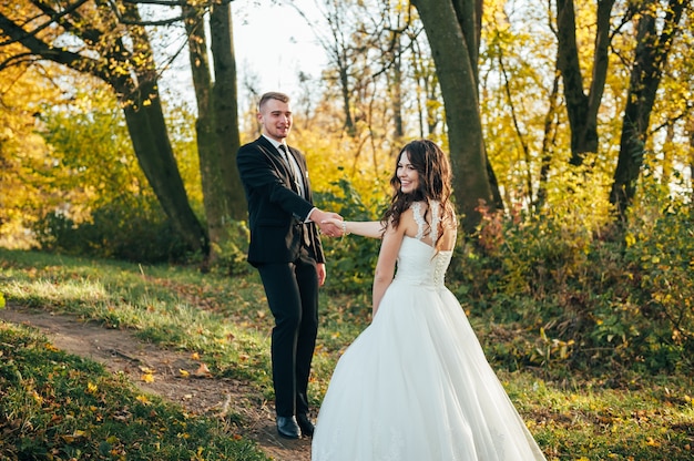 Gelukkig en verliefd bruid en bruidegom lopen in herfst park op hun trouwdag