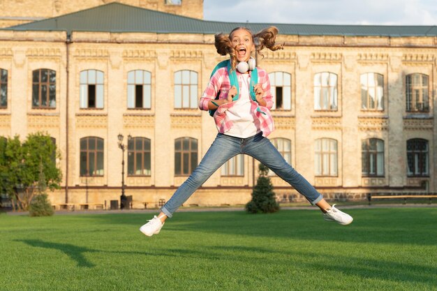 Gelukkig energiek tienermeisje dat buiten op het schoolplein springt Kennisdag