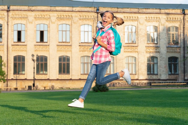 Gelukkig energiek tienermeisje dat in openlucht op het schoolplein springt