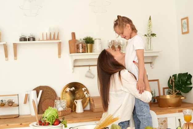 Gelukkig familie gezond leven concept. moeder knuffelt haar dochter in de keuken tijdens het koken.