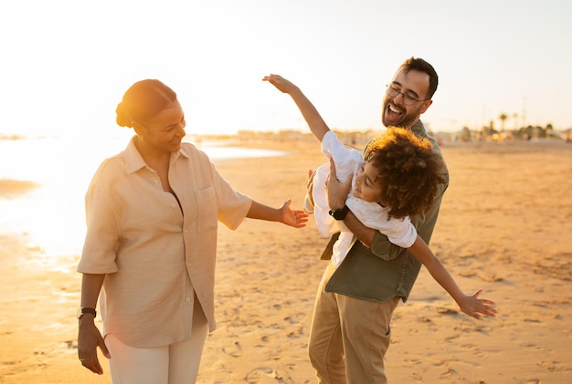 Gelukkig familieconcept jonge moeder, vader en hun zoon die plezier hebben op het strand waar ouders voor de gek houden