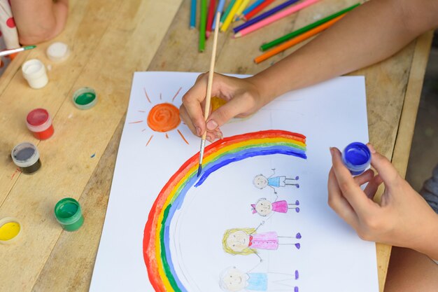 Gelukkig familieconcept. Kind tekent op een vel papier: vader, moeder, jongen en meisje houden elkaars hand vast