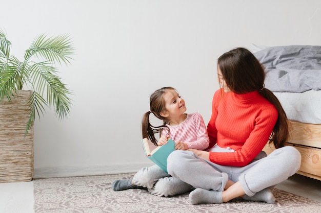 Gelukkig familiemoeder en kind het boek van de dochterlezingsholding die in bed liggen