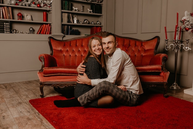 Foto gelukkig familiepaar dat nieuwjaar en kerstmis viert bij versierde kerstboom en slingers