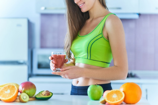 Gelukkig fitness dieet vrouw in sportkleding drinkt een vers fruit smoothie om af te vallen. Vitaminedranken voor gezond eten