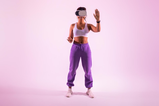 Gelukkig fitte dame die d-technologie en virtual reality-game verkent met een vr-headset over roze neon