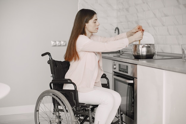 Gelukkig gehandicapte vrouw in rolstoel bereiden van voedsel in de keuken.