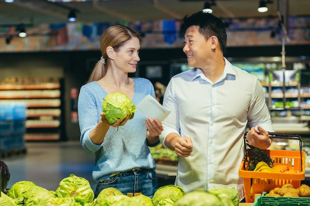 Gelukkig gemengd ras Aziatische paar familie man en vrouw kiezen groenten in supermarkt supermarkt