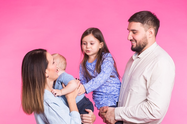 Gelukkig gemengd ras familieportret lachend op roze muur