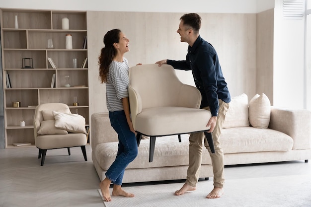 Gelukkig getrouwd stel geniet van het verhuizen naar een nieuw huis opgewonden huiseigenaren huurders man en vrouw die meubels dragen met een leunstoel praten lachen grappen voelen vreugde verhuizing concept