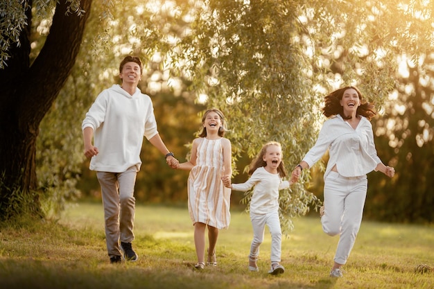 Gelukkig gezin bij zonsondergang Vader moeder en kinderen rennen met plezier en genieten van de zomeravond