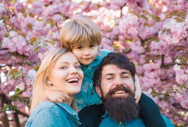 Gelukkig gezin buitenshuis moeder vader en zoon lentetijd portret van gelukkige familie in bloeiende tuin