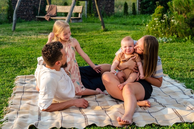 Gelukkig gezin en kleine kinderen die samen plezier hebben, uitrustenxAop een deken in de zomer