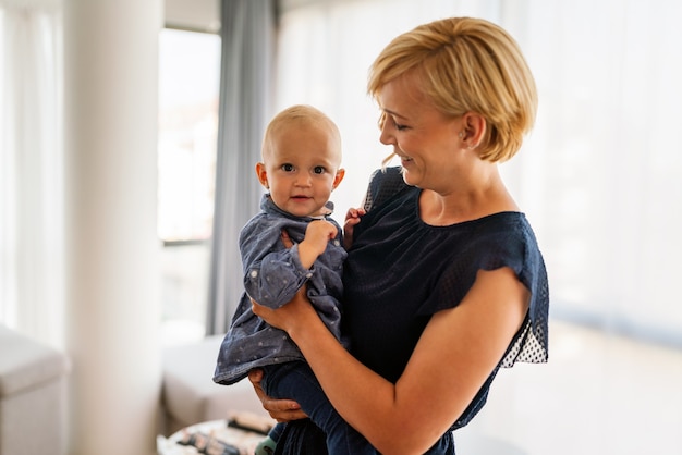 Gelukkig gezin. Jonge mooie moeder en dochtertje spelen, knuffelen, zoenen thuis