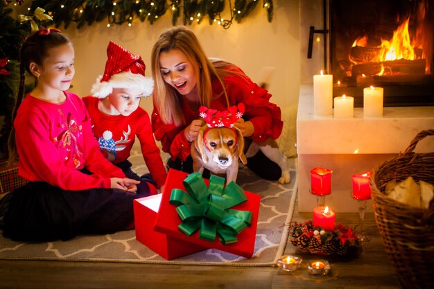 Gelukkig gezin met beigle hond zit bij kerstboom