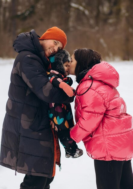 Gelukkig gezin met dochter die plezier heeft in het winterbos Moeder vader dochter wandelen in de sneeuw