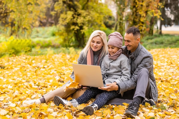 Gelukkig gezin met dochtertje glimlachend gelukkig kijkend naar laptop scherm wandelen in park