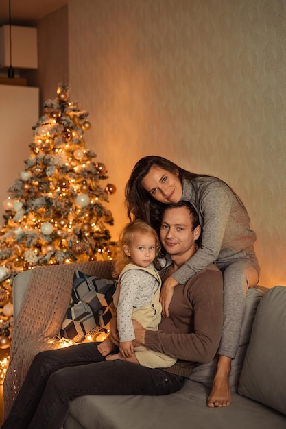 Gelukkig gezin met een kind thuis in de buurt van de kerstboom wachten op het nieuwe jaar