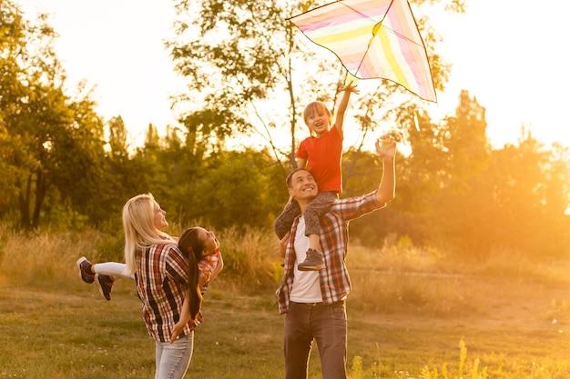 Gelukkig gezin met een vlieger die speelt bij zonsondergang in het veld