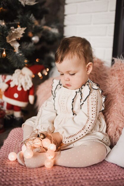 Gelukkig gezin met kind dat Nieuwjaar en Kerstmis viert bij versierde kerstboom en slingers