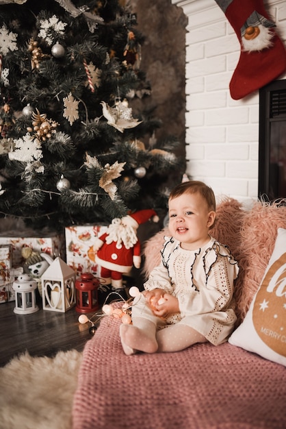 Gelukkig gezin met kind dat Nieuwjaar en Kerstmis viert bij versierde kerstboom en slingers