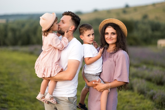 Gelukkig gezin met kleine kinderen op het lavendelveld, liefhebbende vader houdt schattige dochter in de armen