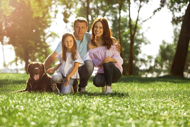 Gelukkig gezin met labrador in het park glimlachen naar de camera