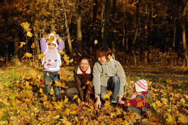 Gelukkig gezin met twee kinderen gooien bladeren in de herfst park