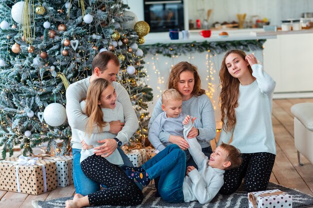 Gelukkig gezin met vier broers en zussen in de buurt van de kerstboom met de huidige dozen. Kerst familie ochtend, kerststemming concept