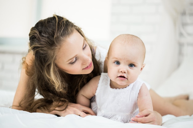 Gelukkig gezin. moeder speelt met haar baby in de slaapkamer.