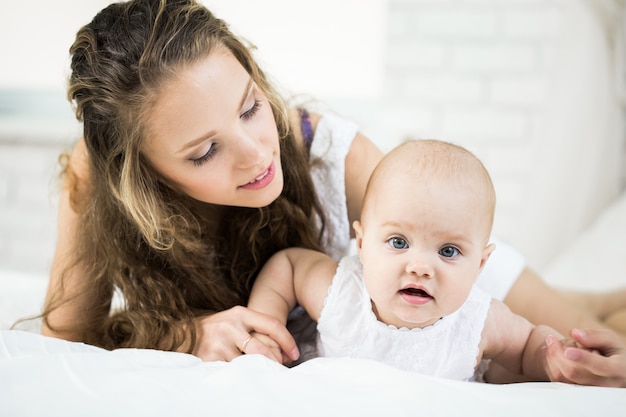 Gelukkig gezin. moeder speelt met haar baby in de slaapkamer.