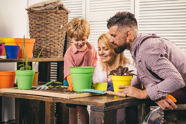 Gelukkig gezin moeder vader en kind Gelukkig gezin met kinderen die plant in pot kweken Jonge ouders en hun kind zijn erg blij