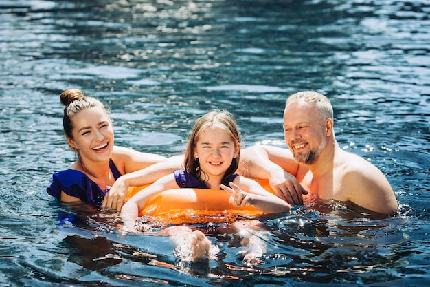 Gelukkig gezin plezier op zomervakantie Vader moeder en kind spelen in zwembad Actief gezond levensstijl concept