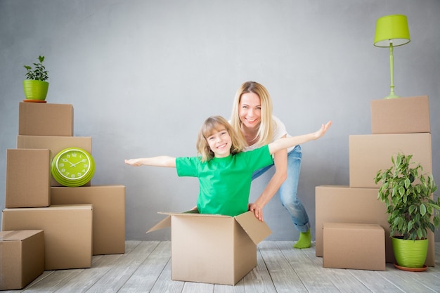 Gelukkig gezin spelen in nieuw huis Moeder en kind hebben samen plezier Verhuisdag