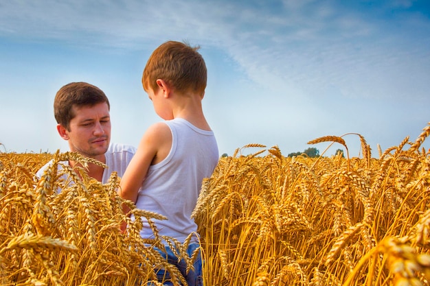 Gelukkig gezin Vader en zoon op het tarweveld Man toont de jongensoor van tarwe