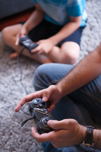 Gelukkig gezin. Vader, moeder en kinderen spelen een videogame Vader en zoon spelen samen videogames op de vloer