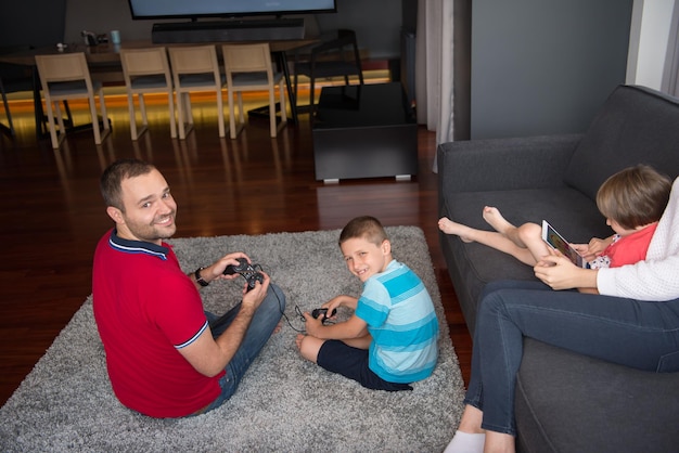 Gelukkig gezin. Vader, moeder en kinderen spelen een videogame Vader en zoon spelen samen videogames op de vloer