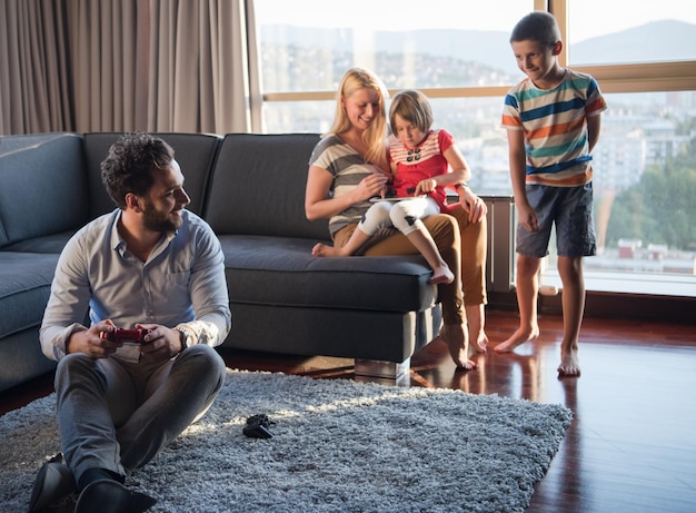 Gelukkig gezin. Vader, moeder en kinderen spelen een videogame Vader en zoon spelen samen videogames op de vloer