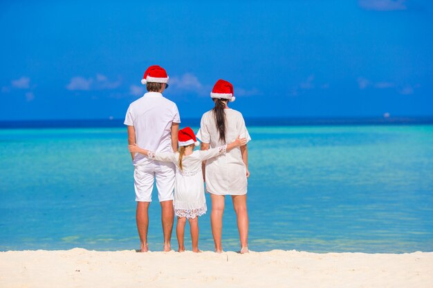 Gelukkig gezin van drie in santa hats tijdens tropische vakantie