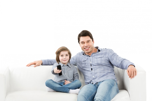 Gelukkig gezin van twee personen, vader en zoon op de bank met een afstandsbediening van tv