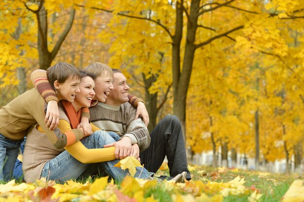 Gelukkig gezin van vier mensen ontspannen in een park in de herfst