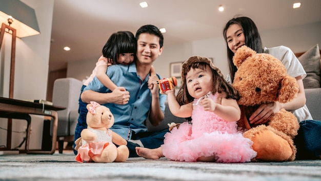 Gelukkig gezinOuders spelen met teddyberen en speelgoed met hun kinderen zittend op het tapijt in de woonkamer thuisWeekendactiviteit gelukkig gezin levensstijlconcept