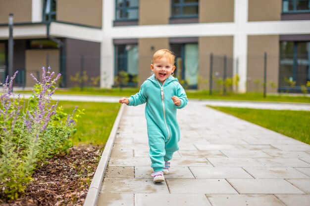 Gelukkig gezond lief babymeisje in het blauw dat over het algemeen plezier heeft in het actieve kind van de stad op een koude dag in de buitenlucht