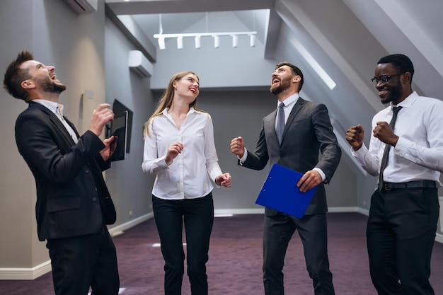 Gelukkig glimlachend commercieel team dat triomf viert met opgeheven vuisten