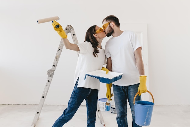 Gelukkig glimlachend getrouwd echtpaar bezig met renovatie reparaties in de kamer van het huis dat zich voorbereidt om te verhuizen