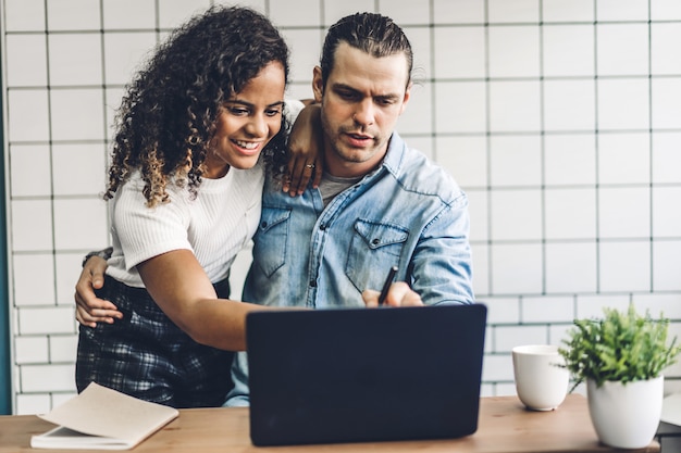 Gelukkig glimlachend paar die met laptop computer samenwerken. Creatieve bedrijfspaar planning en uitwisseling van ideeën in woonkamer thuis