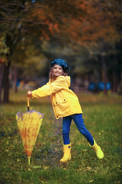 Gelukkig grappig kindmeisje met paraplu in rubberlaarzen