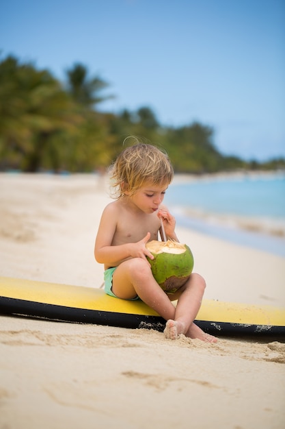 Gelukkig grappig voorschoolse jongen jongetje kokosnoot sap drinken op oceaan strand