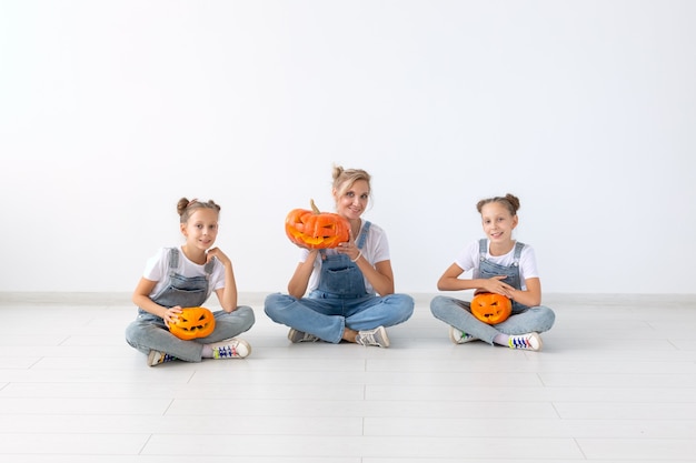 Gelukkig halloween en vakantieconcept - een moeder en haar dochters met pompoenen. Gelukkig gezin