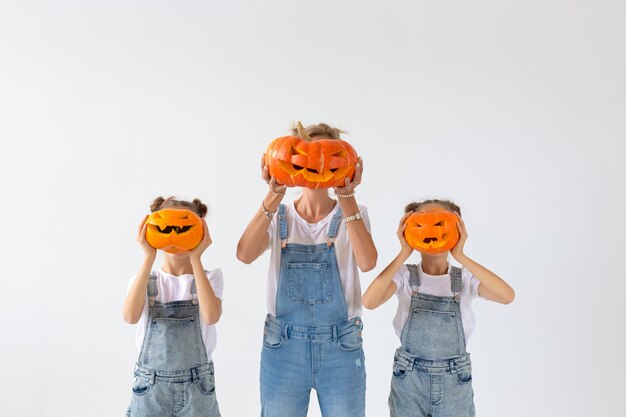 Gelukkig halloween en vakantieconcept - een moeder en haar dochters met pompoenen. Gelukkige familie die zich voorbereidt op Halloween.